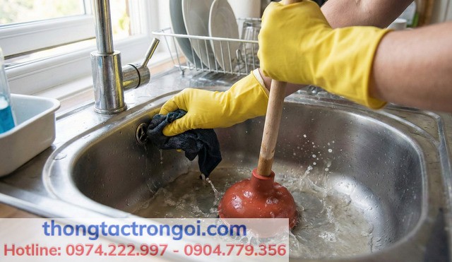 Người dùng đeo găng tay sử dụng cây thụt bồn rửa bát và bịt lỗ thoát tràn để tạo áp lực nén khí tối đa.