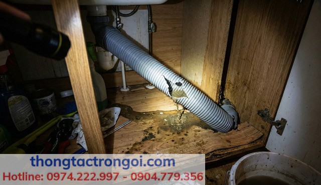 Ống ruột gà nhựa dưới gầm tủ bếp bị bục vỡ gây rò rỉ nước ra sàn gỗ do dùng súng nén khí sai cách.